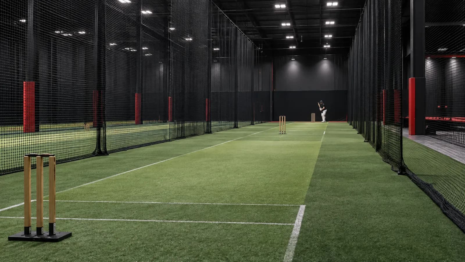 Professional indoor cricket lanes with a player practising in the distance